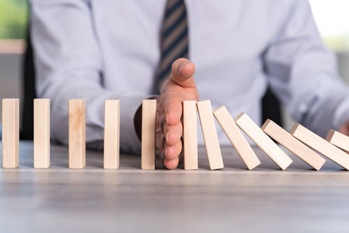 google reputation management metaphor with man stopping domino effect with wooden blocks